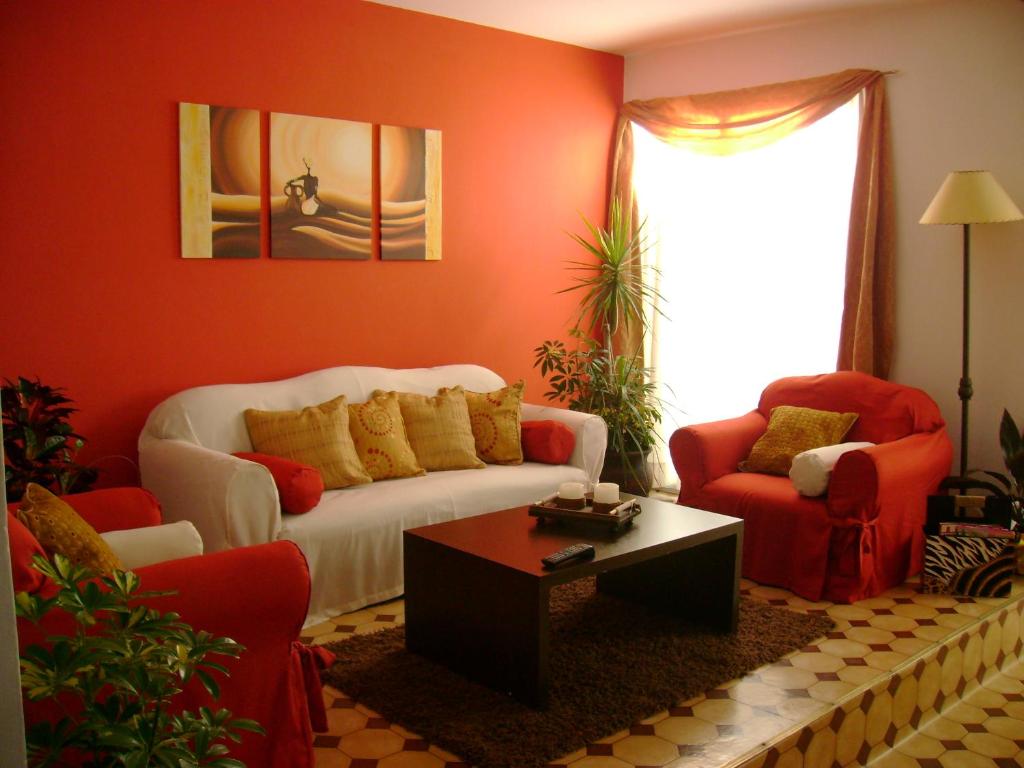 a living room with a white couch and two red chairs at Hotel Minas in Minas