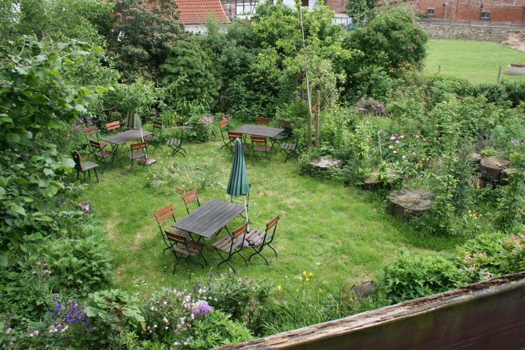 un jardín con mesas, sillas y una sombrilla en Apartments Café Brennnessel en Veltheim
