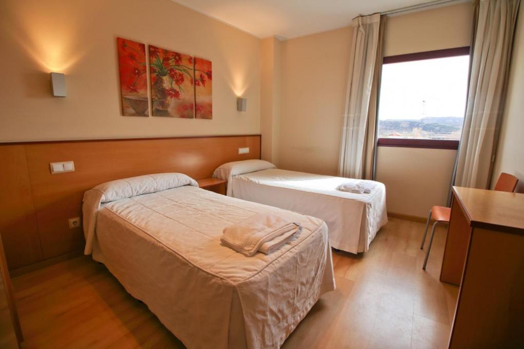 a hotel room with two beds and a window at Hostal Restaurante Taracena in Yunquera de Henares