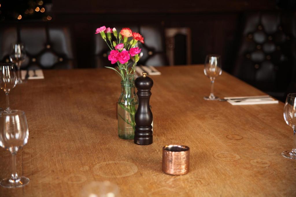 a table with a glass vase with flowers in it at The Jug And Bottle in Heswall
