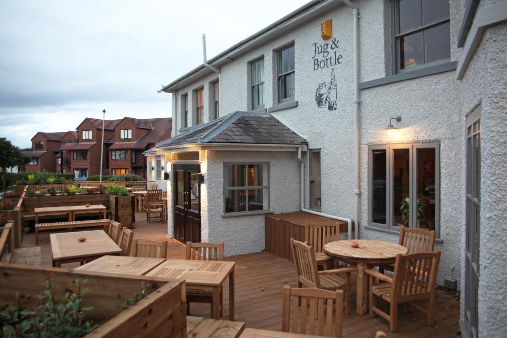 a patio with tables and chairs outside of a building at The Jug And Bottle in Heswall