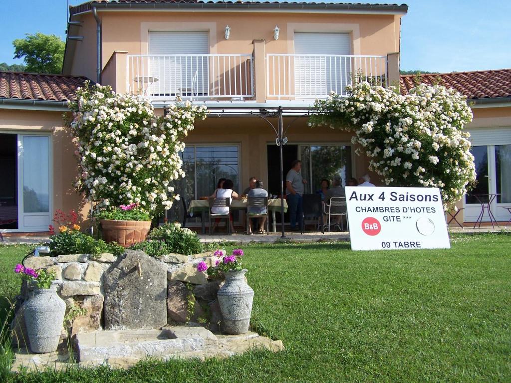 um sinal em frente a uma casa com flores em Aux 4 Saisons em Tabre