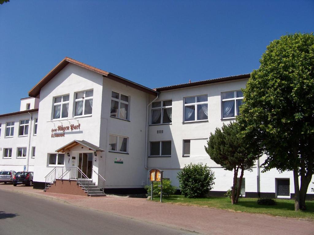 un gran edificio blanco con un árbol delante en Hotel Rügen Park KG, en Gingst