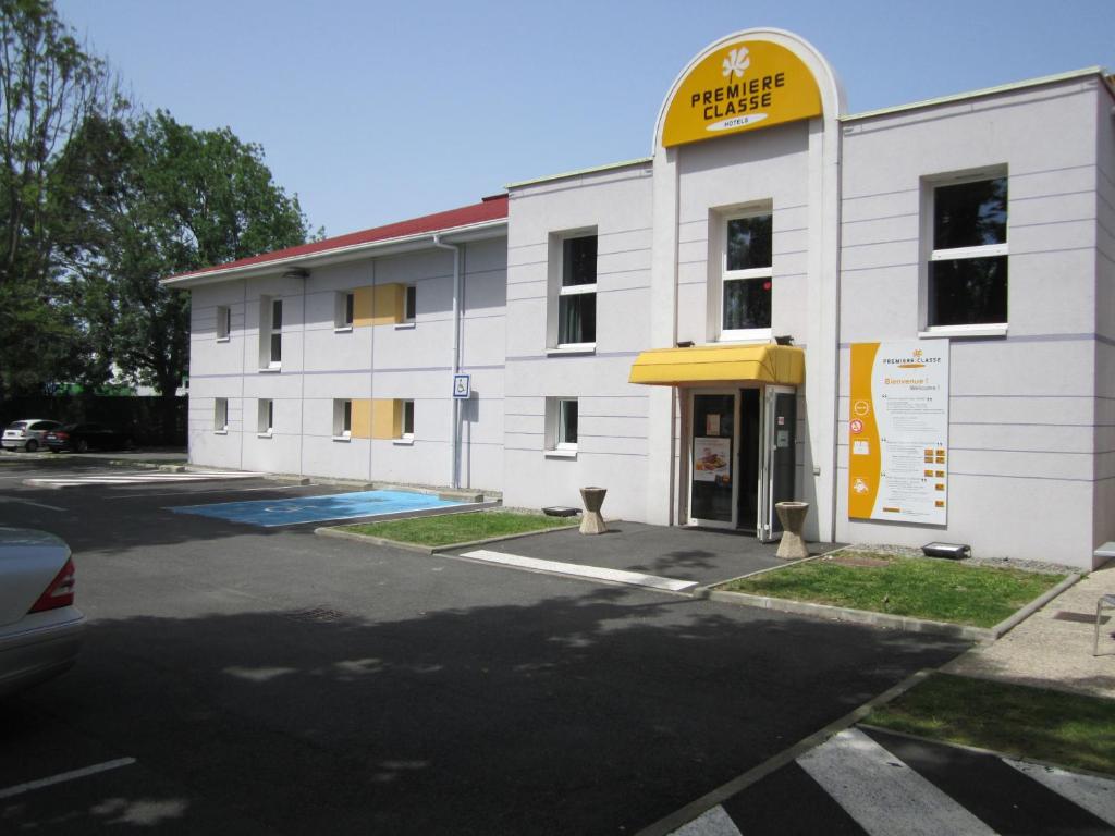 ポーにあるPremiere Classe Pau Est-Bizanosの黄色の看板が立つ白い建物