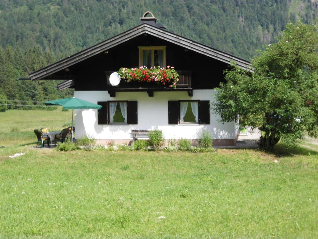 a white house with a balcony with flowers on it at Seewiesenalm in Reit im Winkl