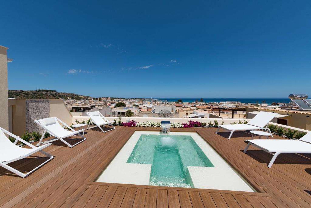 a pool on the roof of a building with chairs and a view at Artemide Hotel in San Vito lo Capo