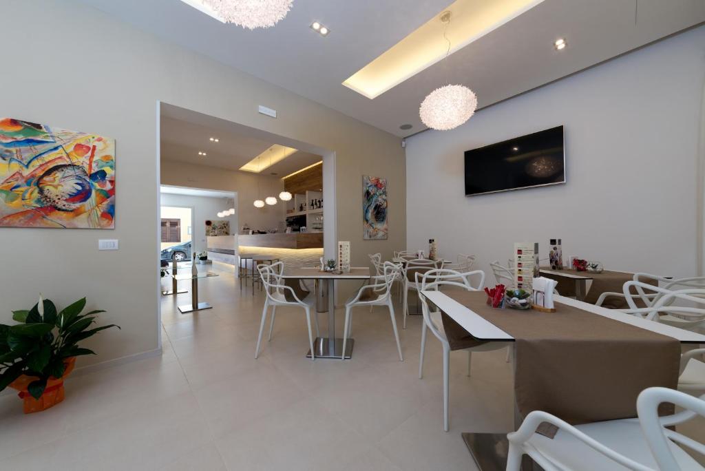 a dining room with white tables and white chairs at Artemide Hotel in San Vito lo Capo