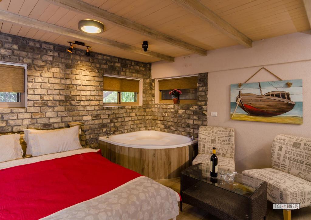 a bedroom with a tub and a bed and a chair at Dream Cabin in Tiberias
