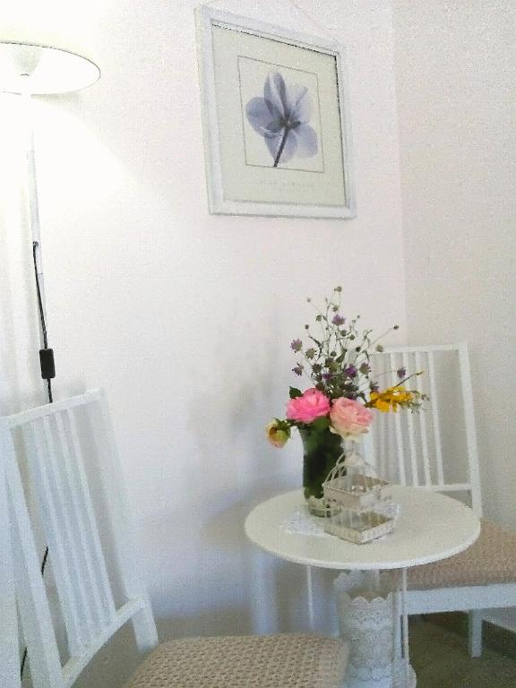a table with a vase of flowers on a table between two chairs at Message in a Bottle Bed and Breakfast in Camporosso