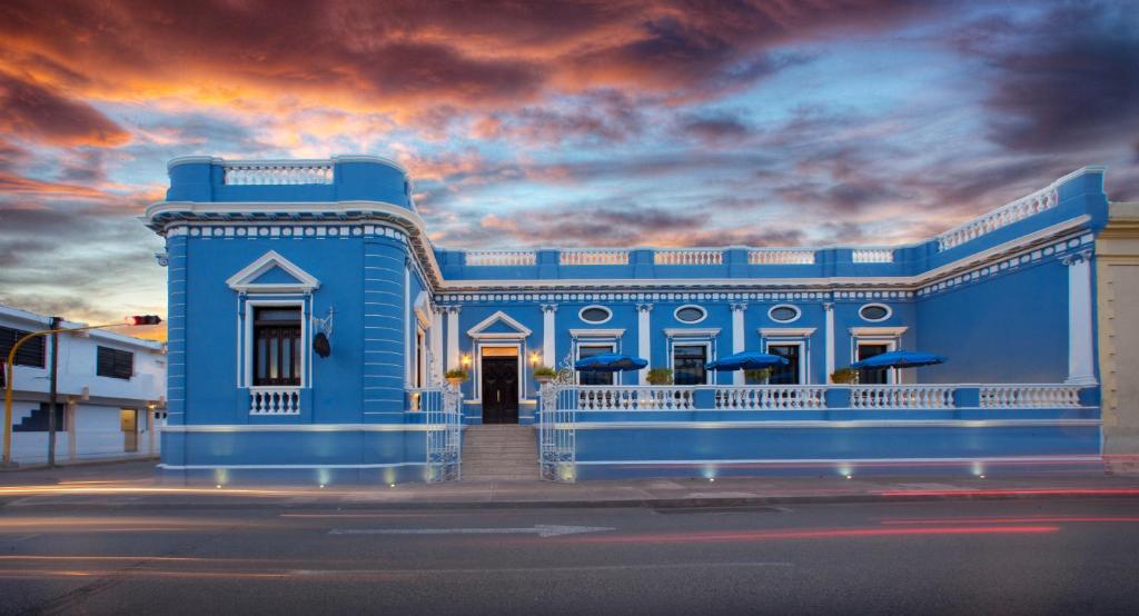 un edificio azul en una calle con un cielo nublado en Casa Azul Monumento Historico en Mérida