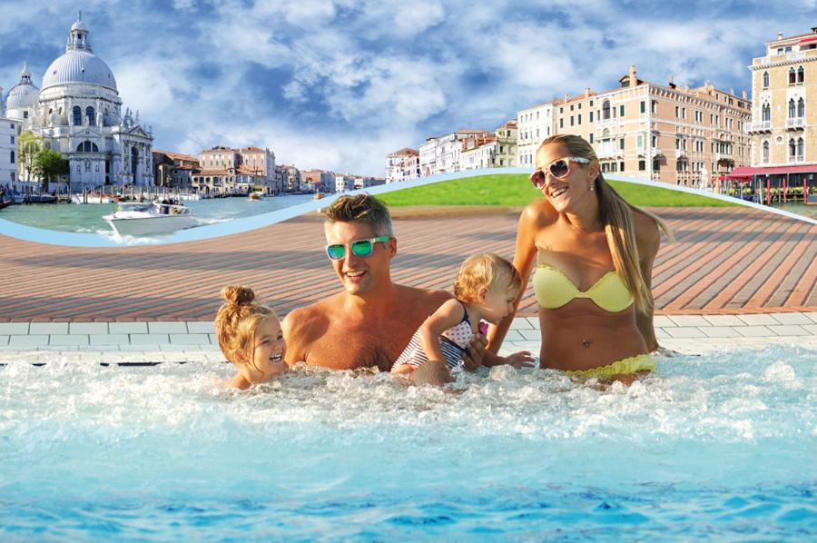 a man and a woman and two children in a swimming pool at Camping Village Miramare in Cavallino-Treporti