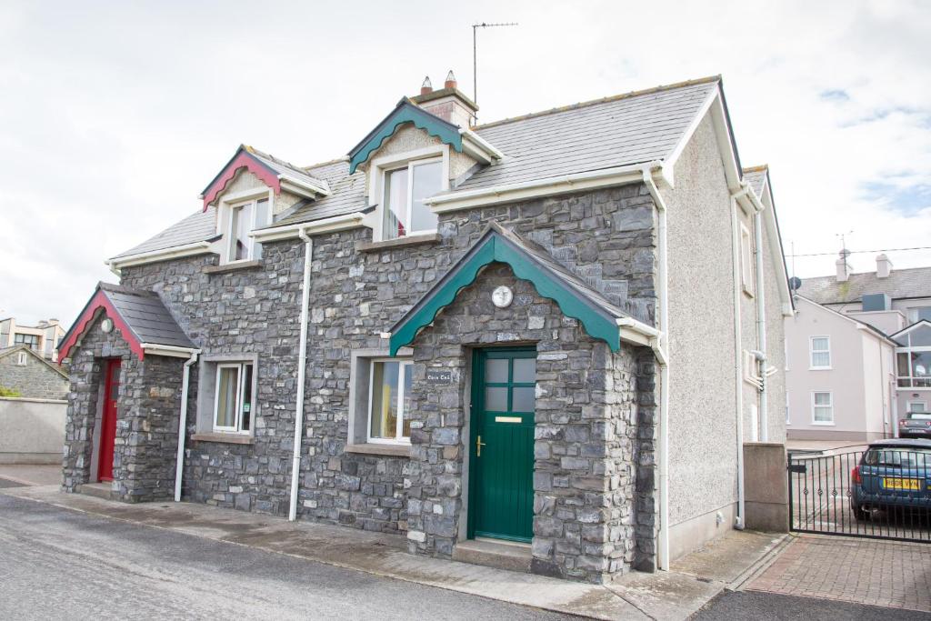 una casa de piedra con una puerta verde en una calle en Ceol na Mara Holiday Homes - Cois Tra & Cor na dTonn en Enniscrone