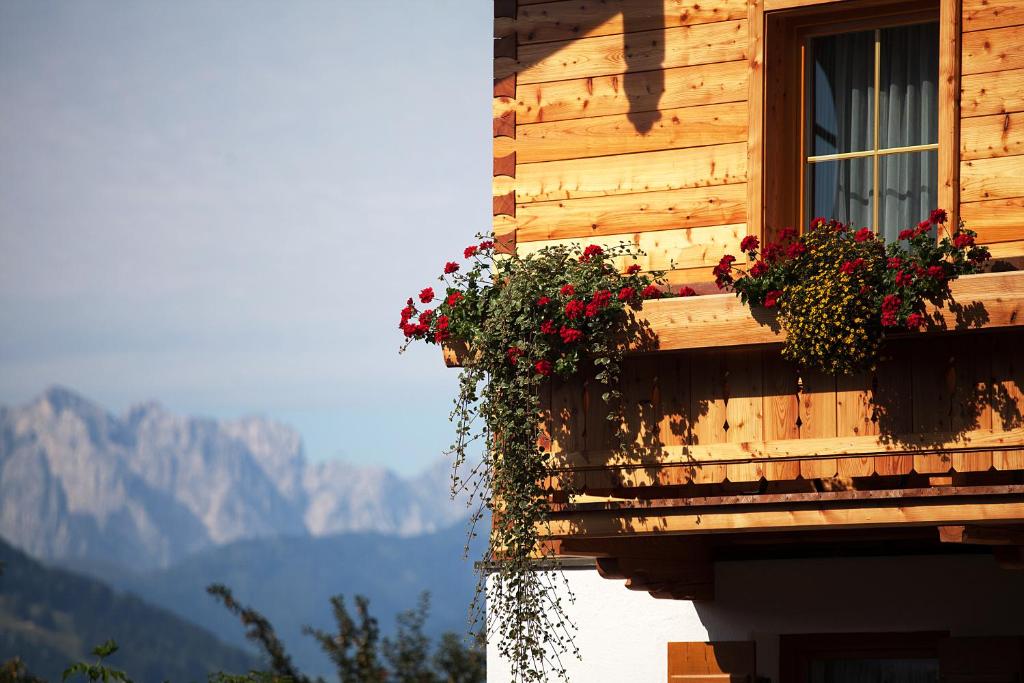 a building with flowers on a window with mountains in the background at Theresenhof in Reit im Winkl