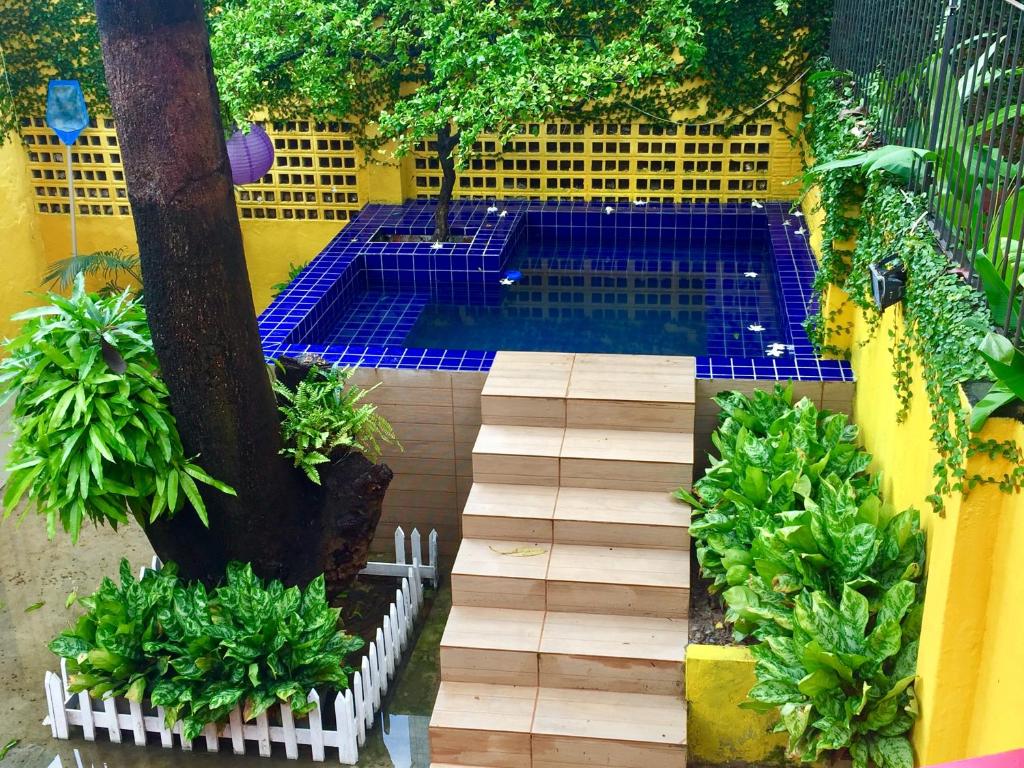 a swimming pool with a wooden walkway in a garden at Cosmopolitan Hostel in Recife