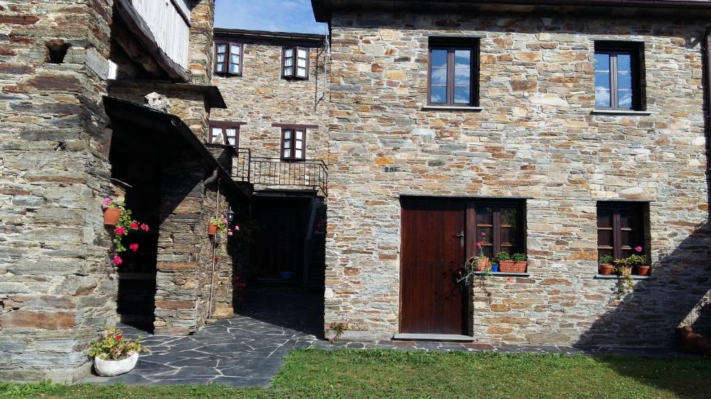 a brick building with a wooden door and a courtyard at Apartamentos Los Castros in San Tirso de Abres