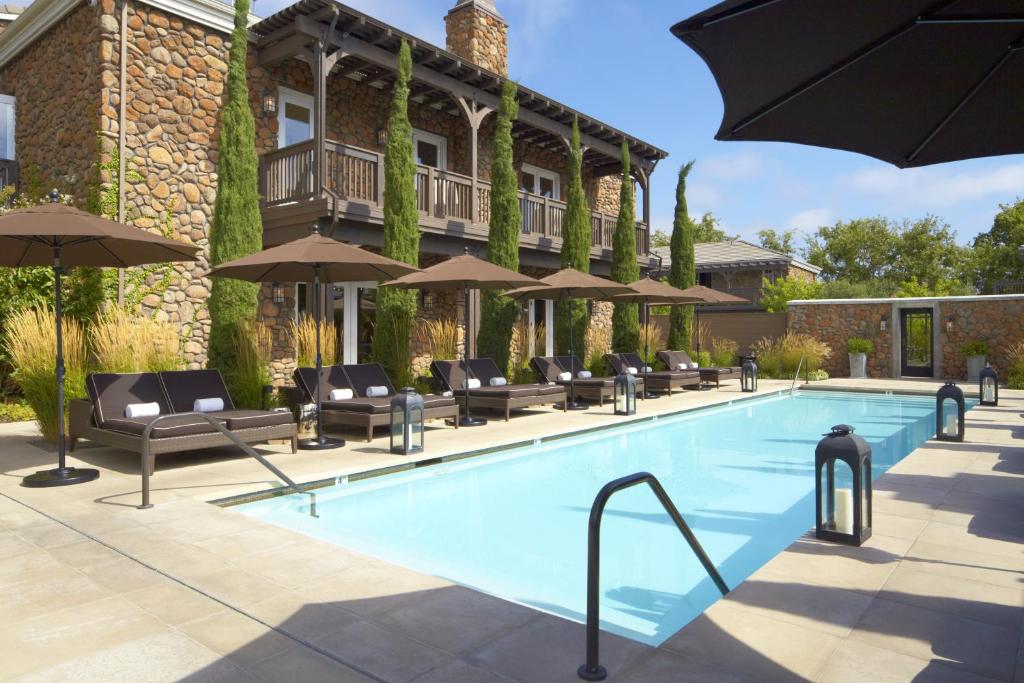 a pool with chairs and umbrellas next to a building at Hotel Yountville in Yountville
