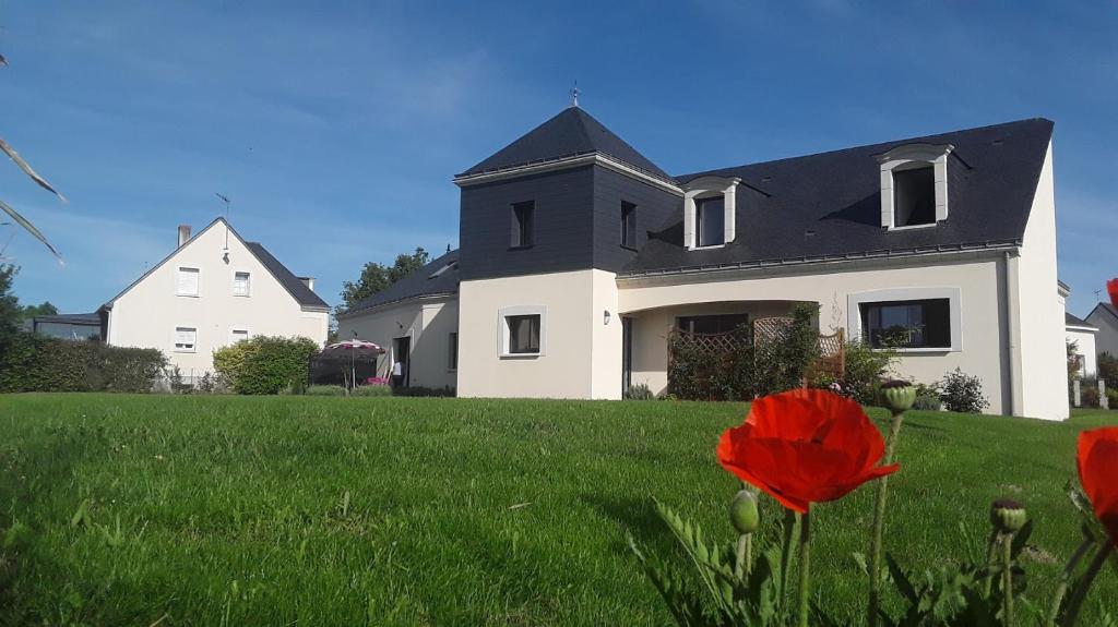 a white house with a red flower in the grass at Logis de l'Hermitage in Le Louroux-Béconnais