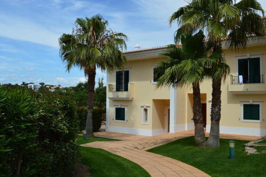 a house with two palm trees in front of it at Villa Formosa Golf in Quinta do Lago