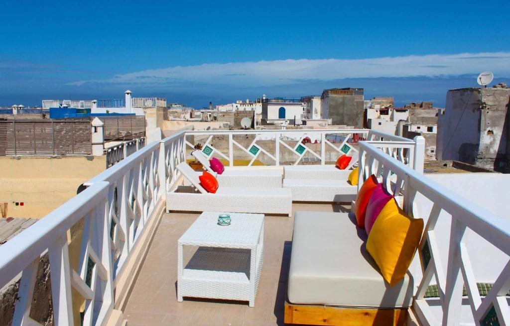 a balcony with white benches and a view of a city at Jennat El Mossafir-Riad privé avec services in Essaouira