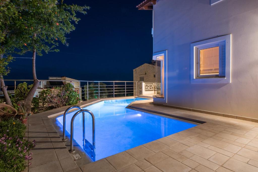 a swimming pool in the backyard of a house at night at Pantanassa Villas in Agia Marina Nea Kydonias