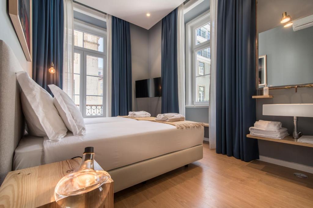 een slaapkamer met een bed en 2 ramen bij Esqina Urban Lodge in Lissabon