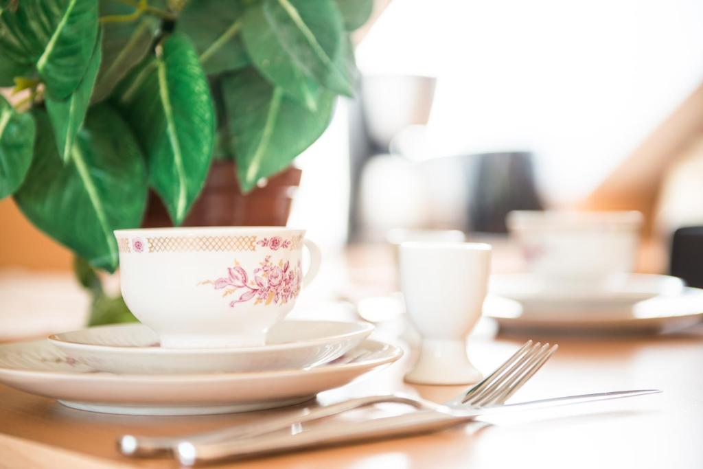 una mesa con platos y tazas y una planta en Ferienwohnung Salzwedel, en Salzwedel