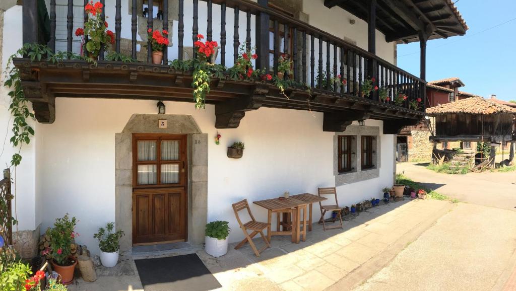 a house with a wooden door and a table and a balcony at A Pie De Picos in Caño