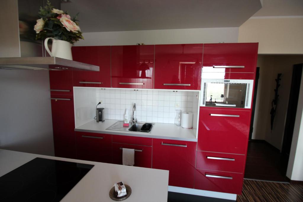 czerwona kuchnia ze zlewem i czerwonymi szafkami w obiekcie Apartament Podgórna 12 w Toruniu