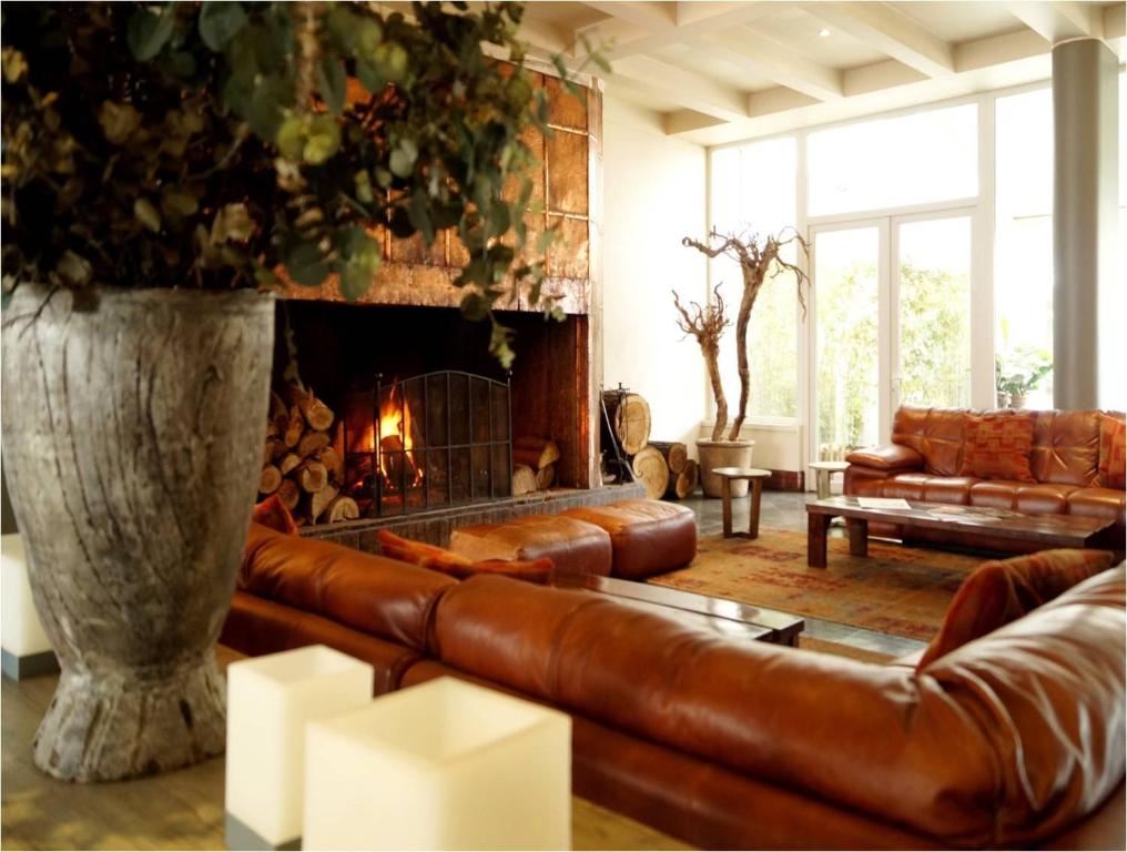 a living room with a leather couch and a fireplace at Hotel Boutique Raíces in Curicó