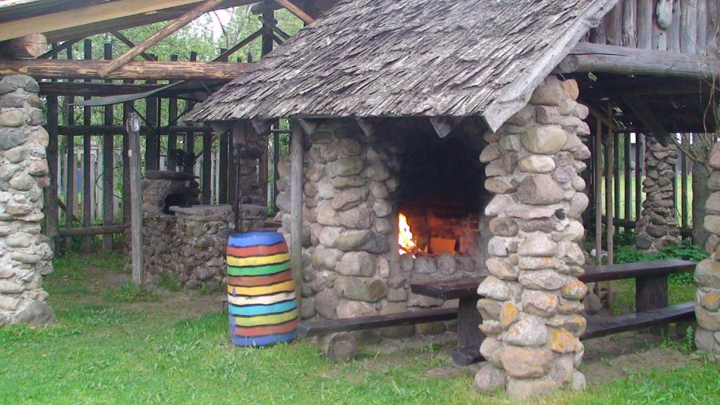 un pequeño edificio de piedra con chimenea y una pila de troncos en TammeKännu Kämpingud, en Mammaste