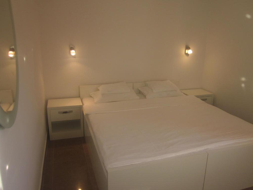 a small bedroom with a white bed with two pillows at Apartments Danilo Kažanegra in Sveti Stefan