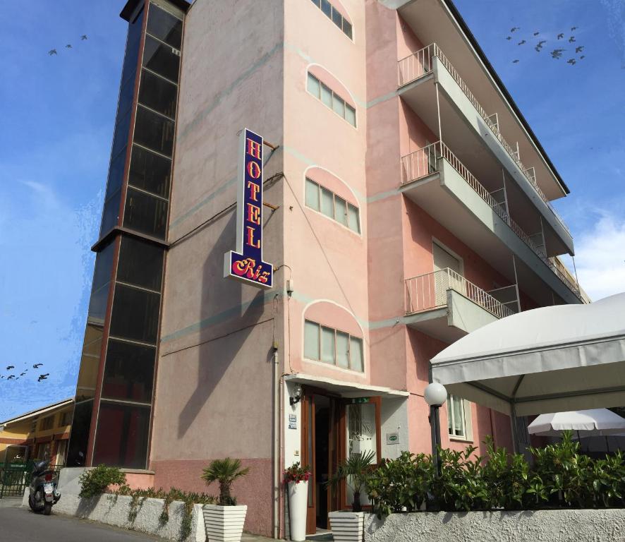 a pink building with a hotel sign in front of it at Hotel Riz in Finale Ligure