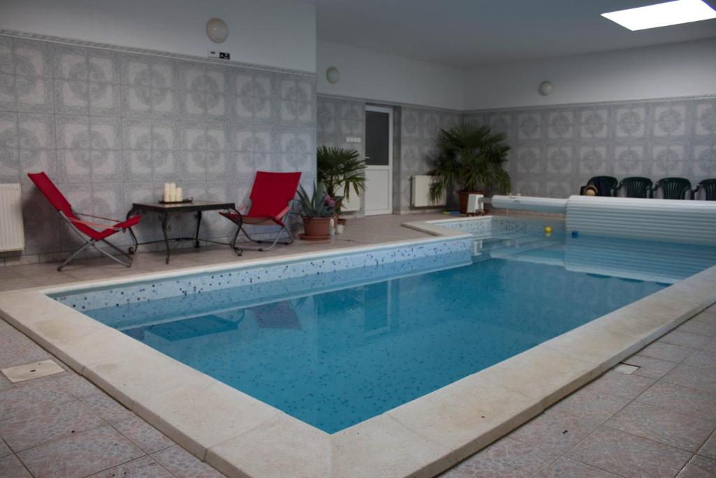 a swimming pool with red chairs and a table next to it at Holiday Home Melinda in Ceglédpuszta