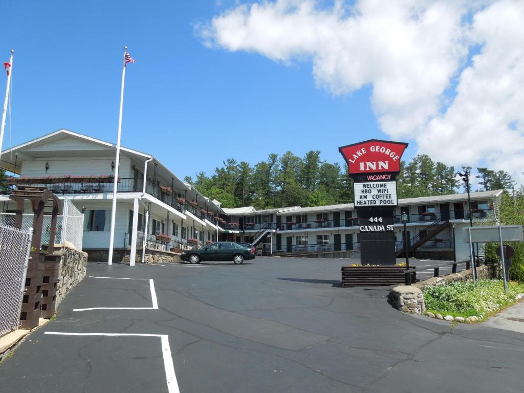 un edificio con un cartel delante de un aparcamiento en The Lake George Inn, en Lake George