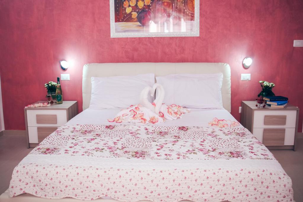 ウジェントにあるIl Sorriso B&Bのピンクの壁の白いベッドが備わるベッドルーム1室