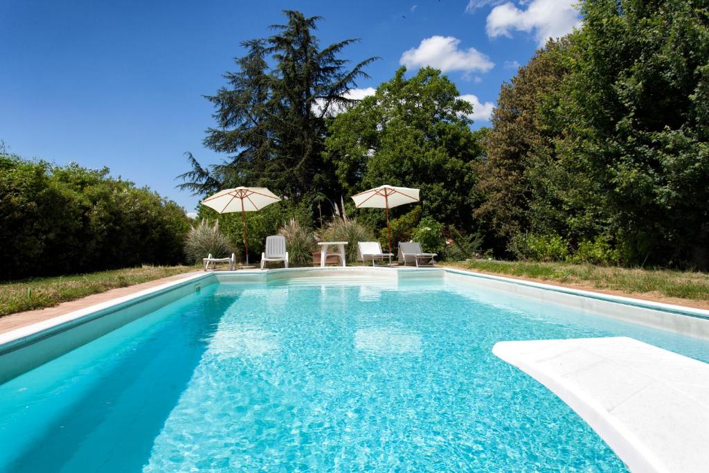 una piscina con 2 sillas y sombrillas en Il Ducato, en Cortona