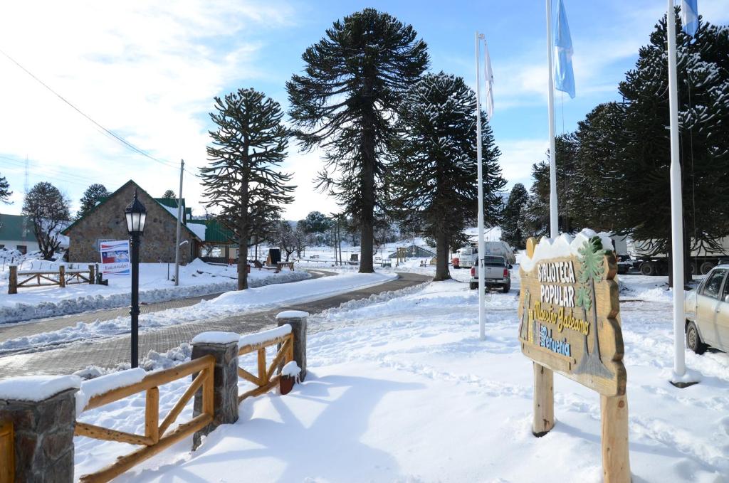 una calle cubierta de nieve con un cartel y una bandera en Milagros de Montaña en Villa Pehuenia