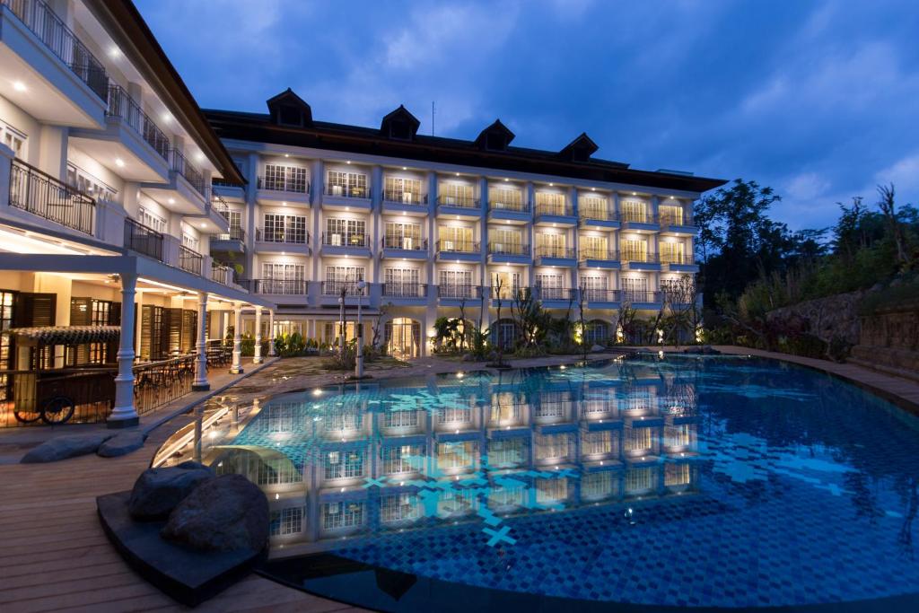 a hotel with a large swimming pool at night at Plataran Heritage Borobudur Hotel in Borobudur