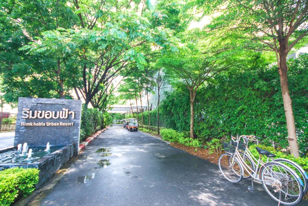 una strada con due biciclette parcheggiate accanto a un cartello di Rimkhobfa Urban Resort a Samutprakarn
