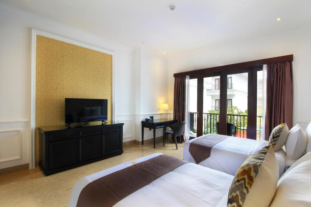 a hotel room with two beds and a flat screen tv at Grand Palace Hotel Sanur - Bali in Sanur