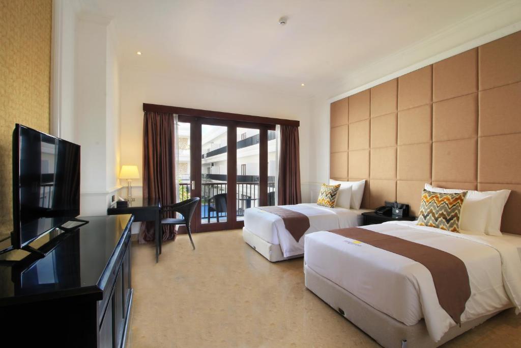 a hotel room with two beds and a flat screen tv at Grand Palace Hotel Sanur - Bali in Sanur