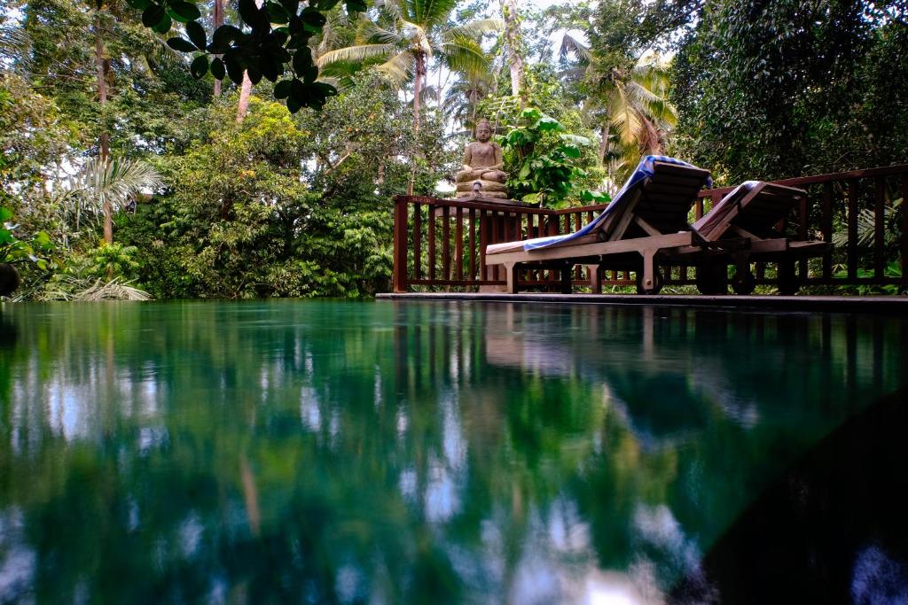 - une piscine avec 2 chaises longues à côté de l'eau dans l'établissement Harum Sari Ubud Private Villa, à Ubud