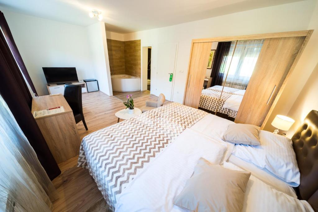 a hotel room with two beds and a television at Villa Gradski Vrt in Osijek