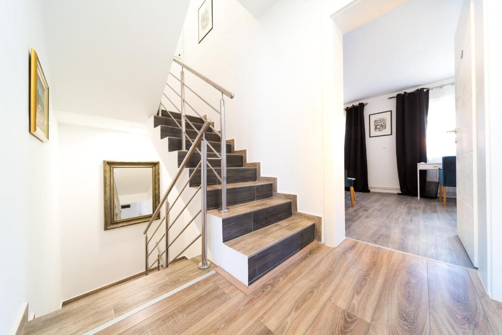 a staircase in a living room with wood floors and a mirror at Villa Gradski Vrt in Osijek