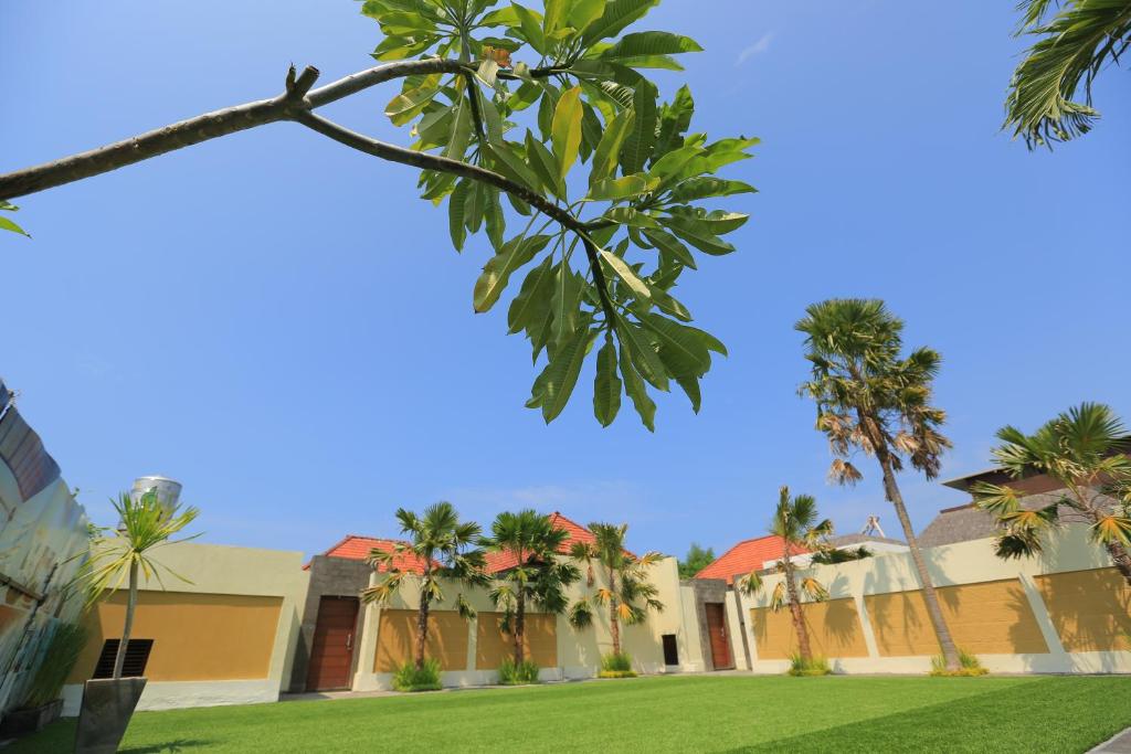 a house with palm trees and a lawn at Putri Bali Villa in Seminyak