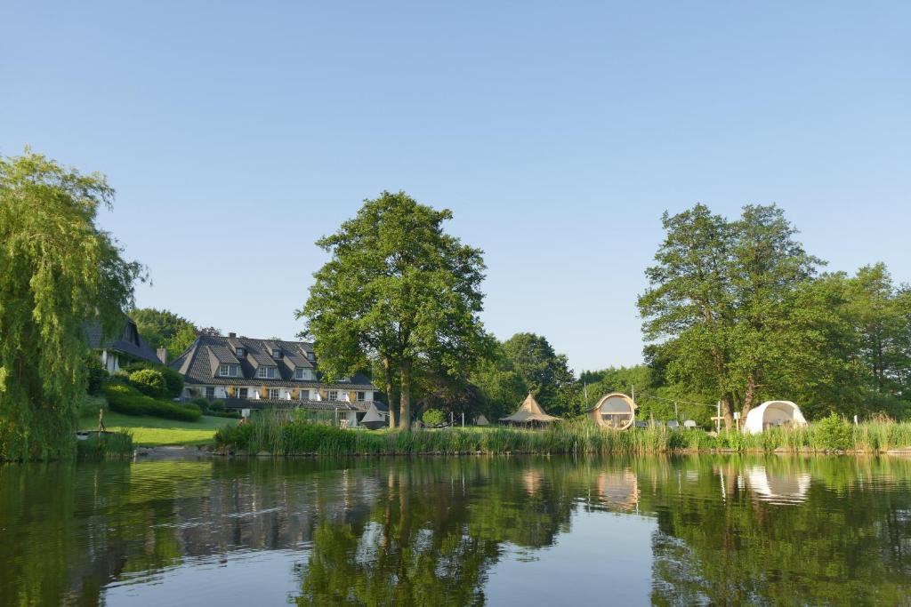 vistas a un lago con casas y árboles en Seehotel Töpferhaus, en Alt Duvenstedt