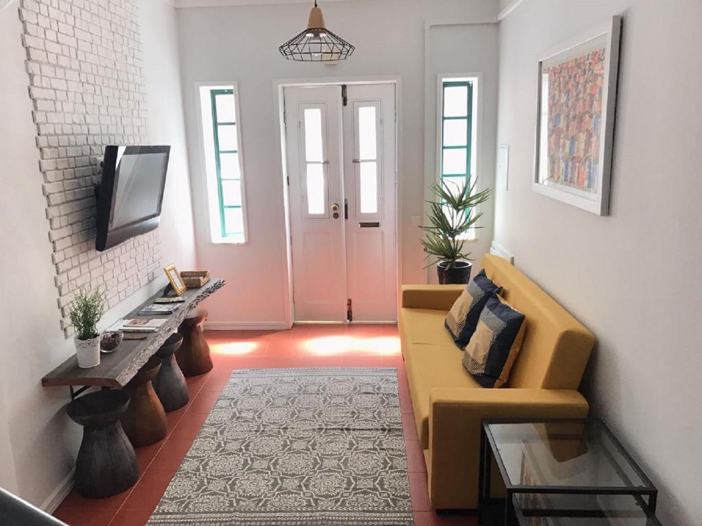 een woonkamer met een gele bank en een tv bij Casa da Ponte Amarela in Aveiro