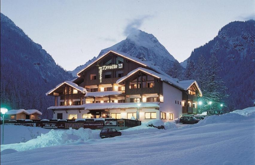 un grand bâtiment au milieu d'une montagne enneigée dans l'établissement Hotel Tyrolia, à Malga Ciapela