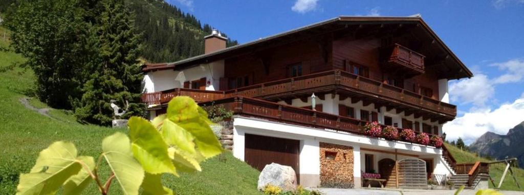 a large building on a grassy hill with at Appartements Birkenhof in Lech am Arlberg