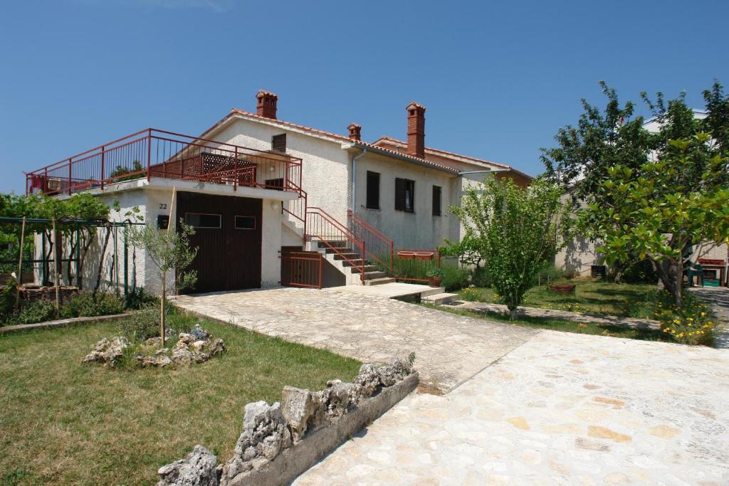 a white house with a balcony and a yard at Apartments Benito in Pješčana Uvala 